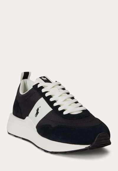 Baskets noir et blanc avec lacets blancs, semelle coussinée et logo Polo sur le côté et la languette, présentées en angle sur fond blanc.