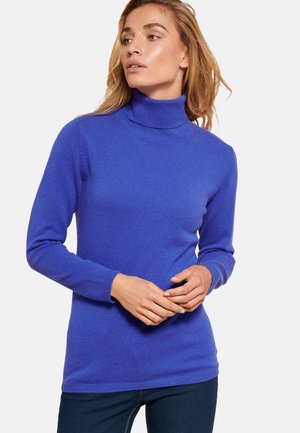 Maglione giromanica blu realizzato in morbido tessuto a maglia, caratterizzato da maniche lunghe e un design aderente, indossato con jeans scuri. Texture liscia, senza motivi.