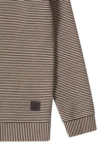 Sweat-shirt à rayures avec des bandes alternées marron et crème, des poignets côtelés, et un petit patch logo sur le côté inférieur. Texture de tissu doux.