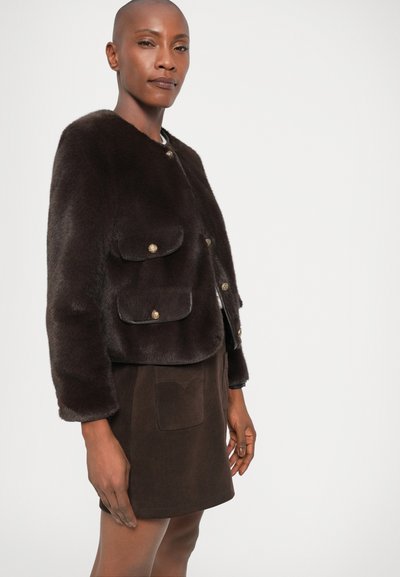 Brun faux fur jakke med rund hals, to frontlommer og gullknapper. Kombinert med et matchende brunt semsket skinnskj�ørt.