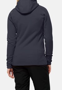 Marinblå softshell-jacka med huva, långa ärmar och en mjuk textur. Tätsittande design med en minimalistisk stil.