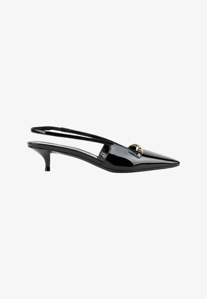 Chaussure slingback en cuir verni noir à bout pointu, avec un petit talon kitten et une petite boucle dorée à l'avant.