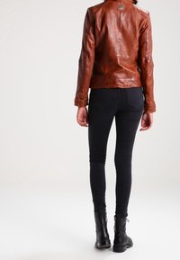 Brun läderjacka med en åtsittande design, sömnad på bakpanelen och etikettdetalj, i kombination med svarta slim fit-jeans och svarta ankelstövlar.