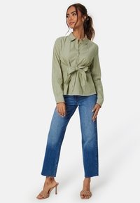 Groen en wit gestreepte overhemden met een geknoopte voorzijde. Gecombineerd met hoge blauwe jeans en tan strappy hakken.