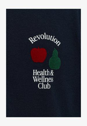 T-shirt bleu marine avec broderie "Club de santé et bien-être Révolution" et motifs de pomme rouge et de poire verte. Tissu en coton, texture lisse.