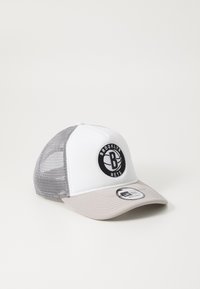 Teherautós sapka fehér elülső résszel, szürke hálós hátsó résszel és bézs napellenzővel. Fekete kör alakú logóval rendelkezik, rajta a "BROOKLYN NETS" felirattal. Texturált anyag.
