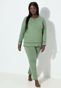 Dwuczęściowa zielona piżama z długim rękawem wykonana z miękkiego materiału, z okrągłym dekoltem, falbankami na rękawach i dole bluzy oraz dopasowanymi spodniami.