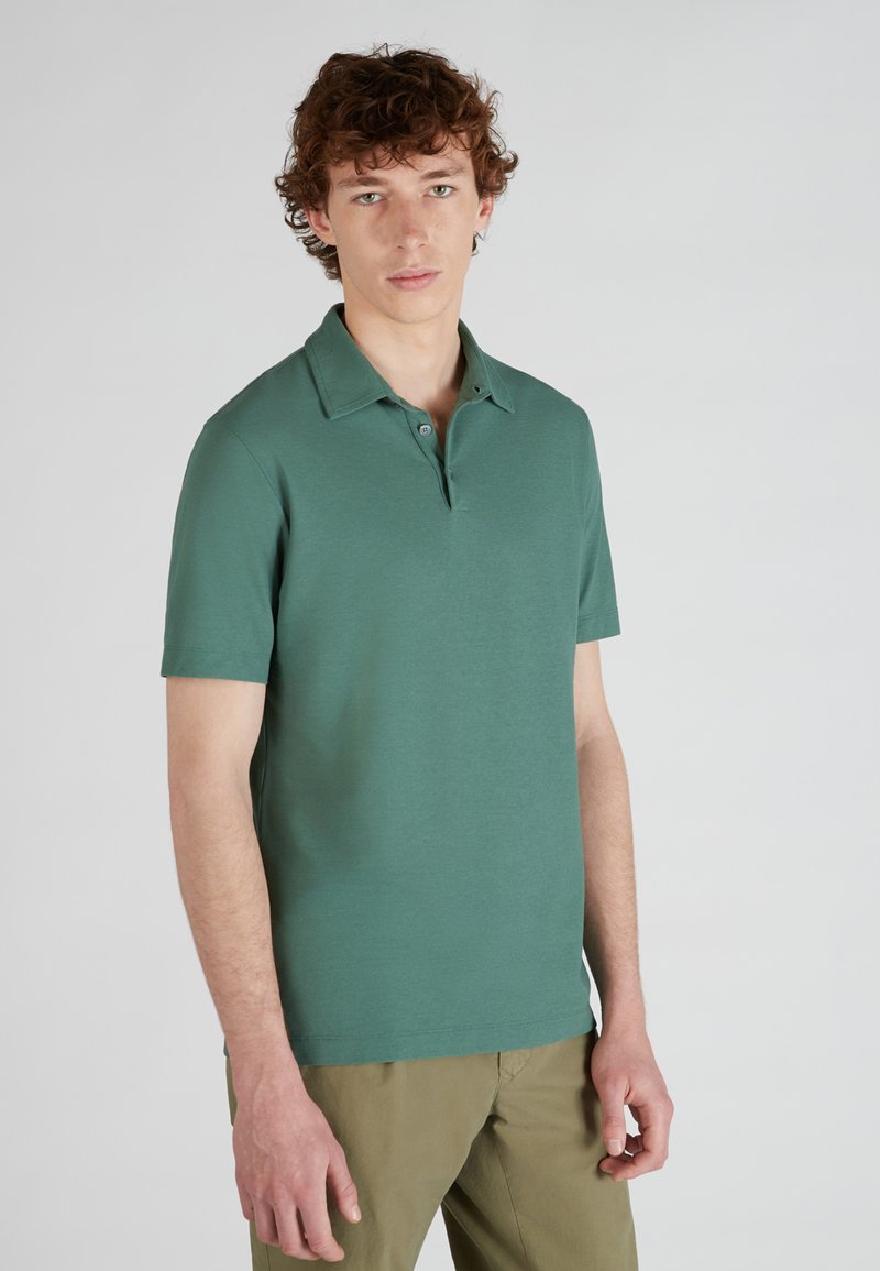 Polo de manga corta en algodón verde, con cuello tipo polo, tapeta de dos botones y una textura suave. Diseño sencillo de color sólido.