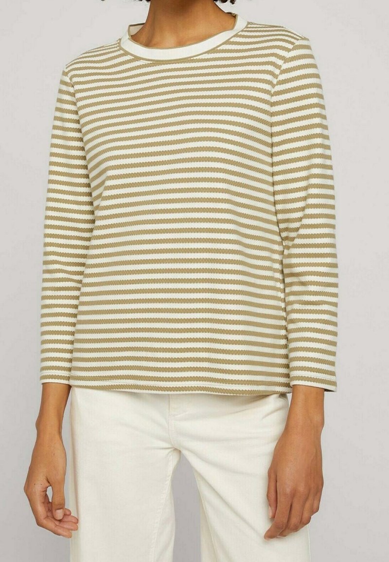 Haut à manches longues rayé beige et blanc, avec un col rond et une coupe décontractée. Le tissu présente un motif texturé.