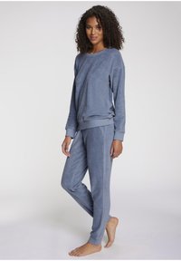 Blue fleece loungewear set featuring a long-sleeve top and tapered pants, both with ribbed cuffs and a soft texture.