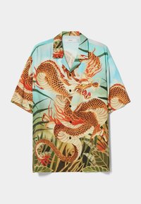 Košile s krátkými rukávy zdobená barevným motivem draka v oranžové, bílé a zelené na světle modrém pozadí; vyrobená z lehké tkaniny.