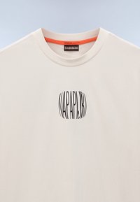 Light beige T-shirt made of cotton with a crew neckline, featuring a black, vertically striped logo design "NAPAPIJRI" on the front.