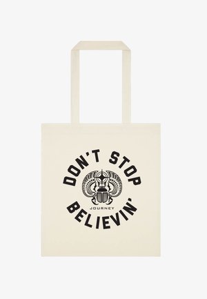 Béžová taška s černým designem scaraba a textem "NEPŘESTÁVEJ VĚŘIT", který je zakřivený kolem, s "JOURNEY" pod ním.