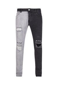 Vaqueros asimétricos que presentan un lado izquierdo de color gris claro y un lado derecho negro, con desgastes y un diseño de corte ajustado.