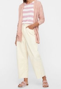 Jasnoróżowy kardigan, pasiasta różowo-biała koszula, kremowe spodnie o szerokich nogawkach i różowe sandały z klamrami. Codzienny strój o miękkich fakturach.