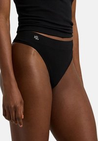 Zwarte katoenen string met een middelhoge taille, met een gladde textuur en witte logo-details op de tailleband. Eenvoudig en minimalistisch ontwerp.