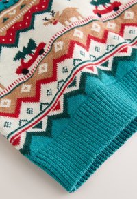 Pletený sveter s tyrkysovým základom a vzorom červených, hnedých a zelených tvarov, zvierat a stromov. Manžety sú lemované žebrovaním.