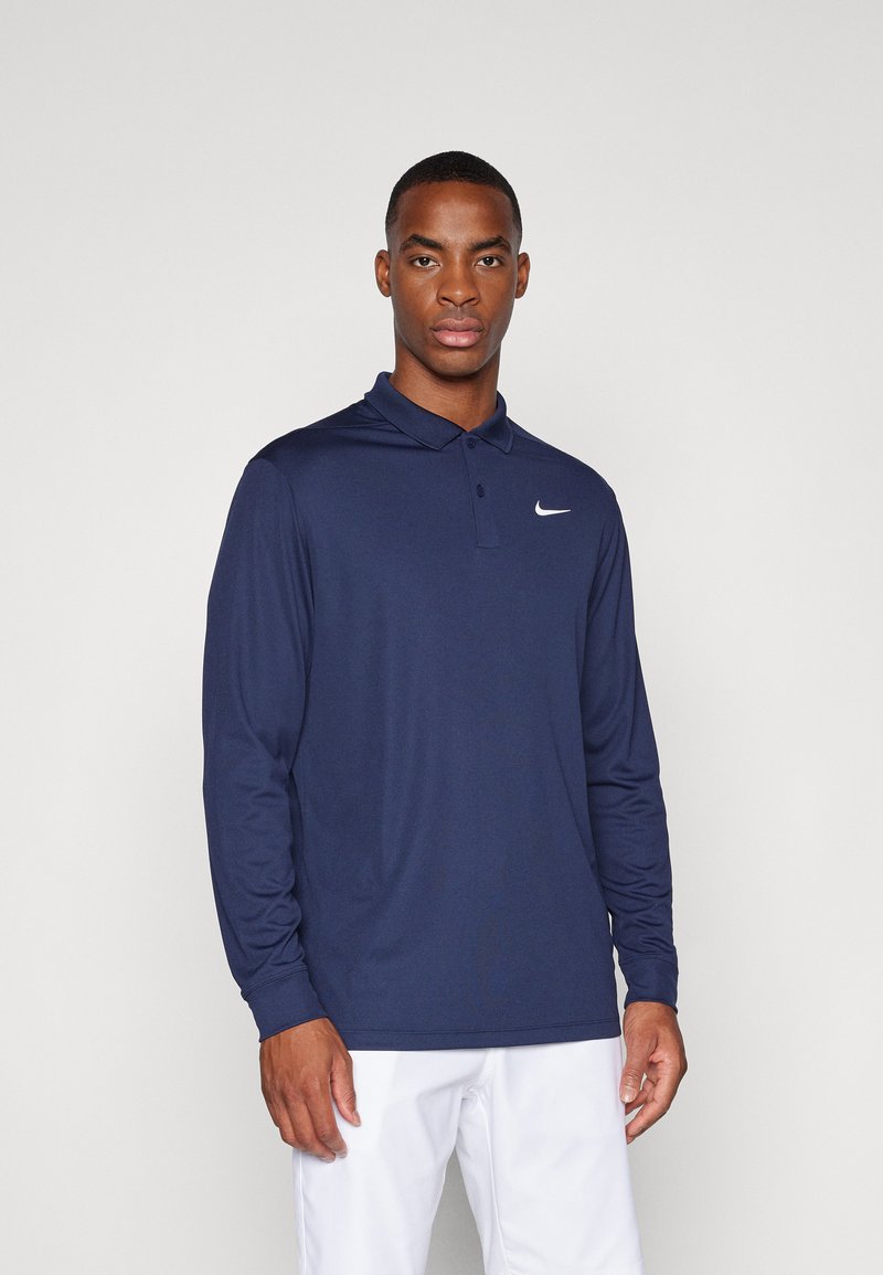 Marineblå långärmad polo med krage, med en vit Nike-logotyp på vänster bröst. Slät, lättviktsmaterial och klassisk passform.