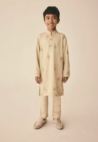 Helles beiges Kurta mit goldener floralem Stickerei, traditionellem Kragen und vorderen Knöpfen, kombiniert mit passenden Hosen und weichen beigen Slippers.