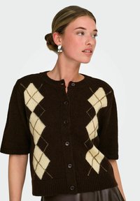 Cardigan tricoté marron à manches courtes, doté d'un motif losange crème et d'un col rond. Fermeture à cinq boutons, ourlet côtelé.