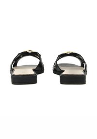 Sandales plates noires avec un accent doré brillant, présentant un design minimaliste et des brides entrecroisées sur une semelle de couleur claire.