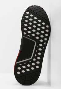 Svart sneakersula med hexagonalt mönster och vita detaljer. Har en texturerad yta och en distinkt logotyp. Rundad häl-design.