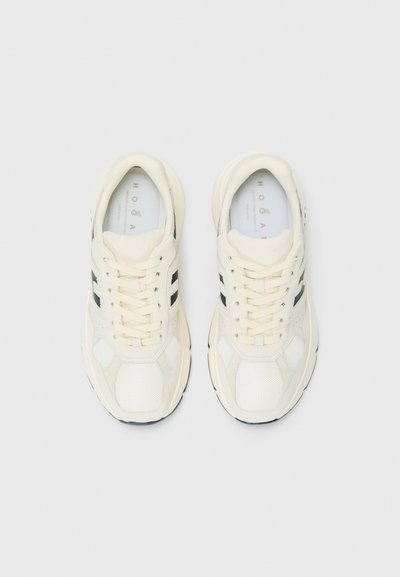 Beige sportieve schoenen van mesh en suede, met zwarte accenten, ronde veters en een gevoerde zool. Logo zichtbaar op de binnenzool.