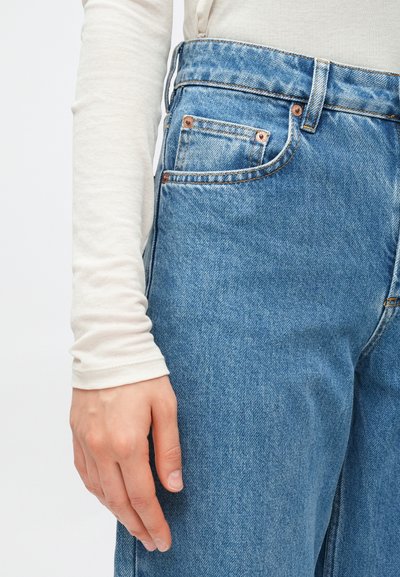 Τζιν παντελόνι από ανοιχτό μπλε denim με ψηλή μέση, εμφανείς ραφές, εμπρόσθια τσέπη και μεταλλικά νίκελ. Απαλή υφή υφάσματος.