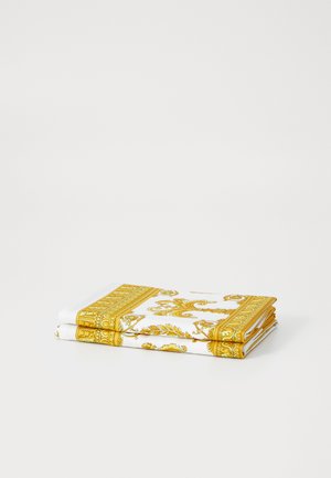 Tissu blanc plié avec des motifs et bordures ornés en or. Forme rectangulaire avec un design détaillé, texture lisse.