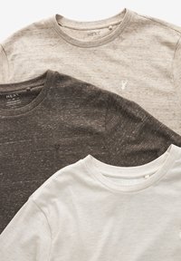 Tre t-shirts med kort ärm i olika nyanser av beige och brunt. Strukturerad tyg med ett subtilt prickigt mönster och en liten logotyp på varje.