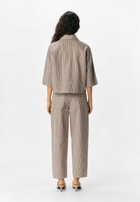 Gestreept twee-delig outfit met een cropped jasje met driekwartmouwen en wijde broek, beide in gedempte beige en bruine tinten.