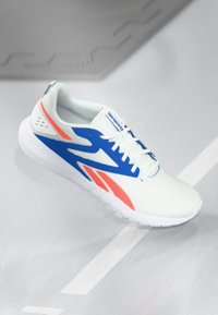 Weiße Reebok-Laufschuhe mit blauen und orangefarbenen Akzenten, weißen Schnürsenkeln und einer dicken weißen Sohle auf einem hellgrauen Boden.