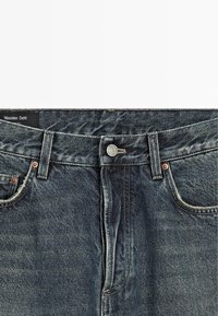 Jeans in denim blu scuro con un classico design a cinque tasche, chiusura con bottone metallico e leggere sfumature. L'etichetta riporta "Massimo Dutti."