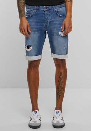 Lichte blauwe denim shorts met een versleten ontwerp, voorzien van scheuren en opgerolde zomen. Draagt het met witte en grijze sneakers.