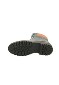 Boot features a rubber sole with a textured grip pattern, a green leather upper, and a brown accent on the heel.