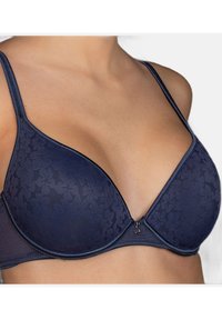 Sujeta de navy azul con un estampado floral, copas acolchadas y un escote en forma de V. Cuenta con tirantes ajustables y un cierre de gancho en la parte delantera.