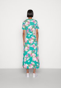 Robe maxi florale en tissu turquoise, dotée de manches courtes, d'un corsage ajusté et d'une jupe fluide à imprimé floral varié en rose et blanc.
