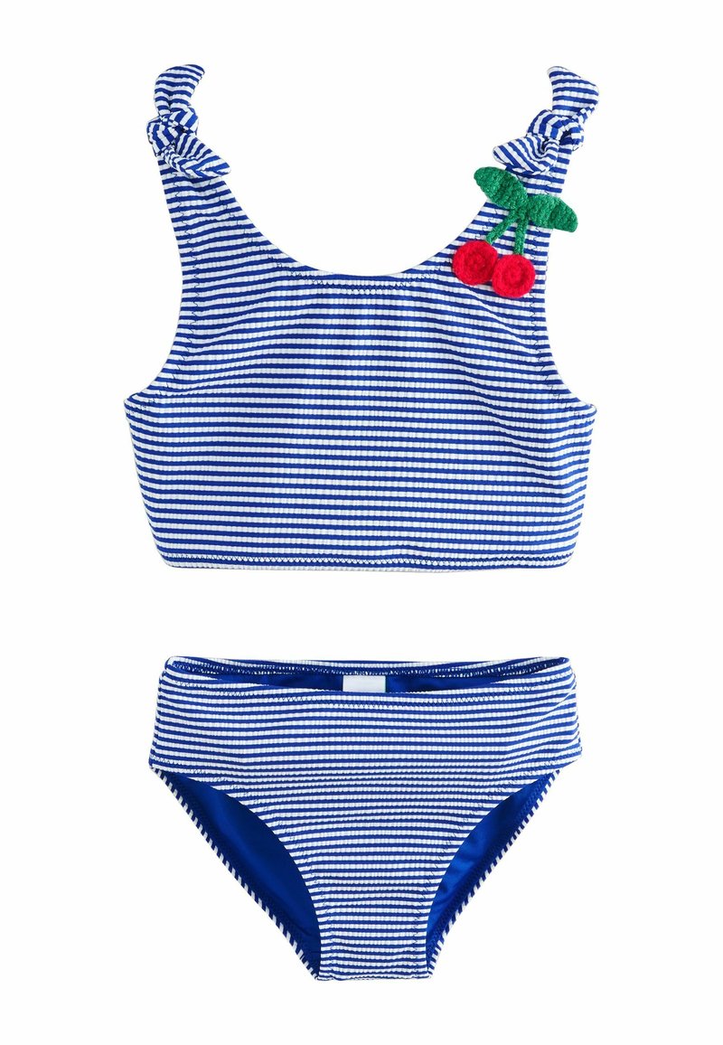 Csíkos kék és fehér bikini szett csomós pánt részlettel. A felsőrész cseresznye appliquéval díszített. Az alsórész összhangban lévő csíkokkal és kék részletekkel rendelkezik.