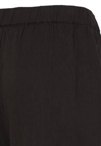 Pantalon en tissu noir avec une taille élastique et des détails de couture subtils visibles en haut.