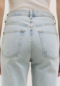 Lichtblauwe denim jeans zijn voorzien van een hoge tailleband, twee achterzakken met rechthoekige kleppen en een zachte, gestructureerde afwerking.