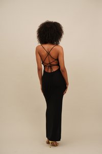 Schwarzes, figurbetontes Maxikleid mit überkreuzten Rückenriemen und Ausschnitt-Detail. Glatte Textur und seitlicher Schlitzakzent. Minimalistisches Design.