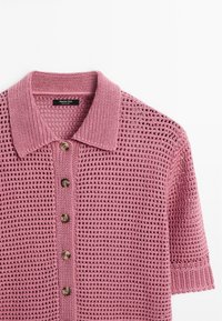 Rosa gestricktes Poloshirt mit einem strukturierten, offen gewebten Design, das einen Kragen und fünf braune Knöpfe auf der Vorderseite aufweist.