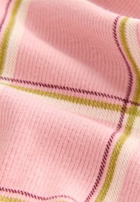 Tessuto rosa strutturato con motivo a costine, caratterizzato da linee a quadri verdi e bianche e piccoli dettagli di cuciture viola sparse.