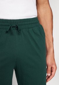 Donkergroene joggingbroek van zachte stof, voorzien van een elastische tailleband met een trekkoord en zijzakken voor extra gemak.