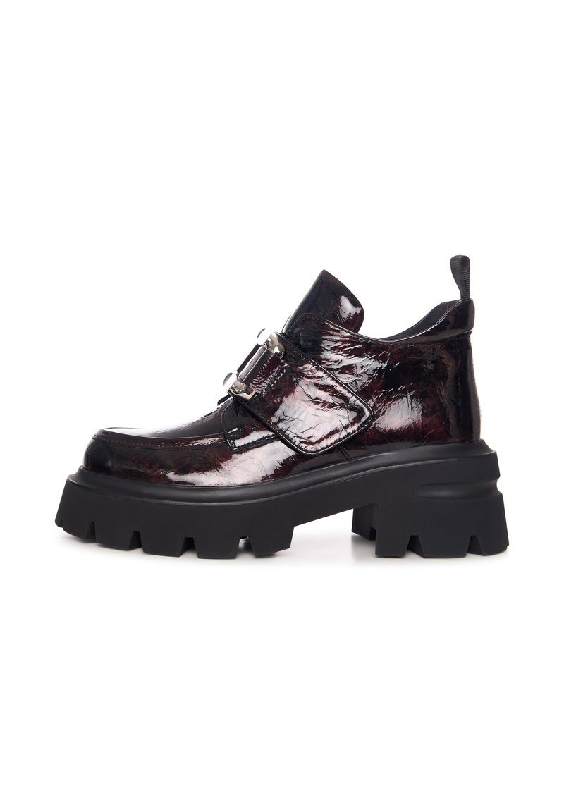 Bottines noires à plateforme épaisse avec une finition bordeaux en vernis, présentant une boucle sur le côté et une tige texturée. Semelle en caoutchouc solide avec de profondes rainures.