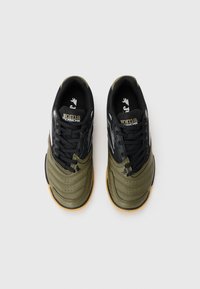 Svarta och olivgröna sneakers med texturerat läder, gummisula och snörningsdesign. Har logotyp och kontrasterande detaljer på sidorna.