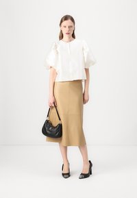 White satin puff-sleeve top, beige leather midi skirt, black handbag, and black heels with patent accents. Clean, minimalistic design.