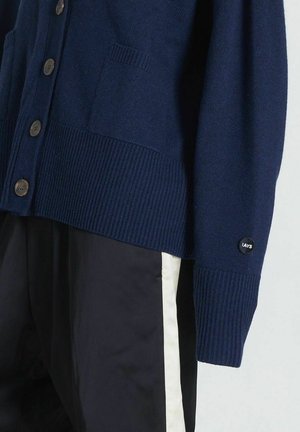 Marineblauer Strickcardigan mit ribbed Bündchen und Saum, verfügt über eine Vordertasche und braune Knöpfe; Logo-Patch am Ärmel.