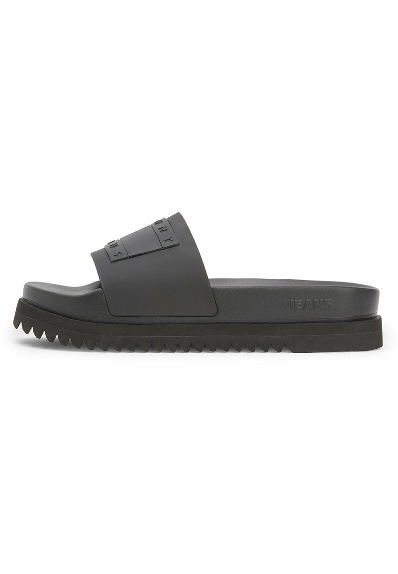 Black slide sandals with a wide strap featuring embossed lettering. Textured sole with zigzag pattern, material appears rubber-like and durable.