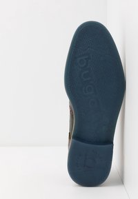 Semelle d'une chaussure avec une partie inférieure en caoutchouc bleu présentant un motif texturé et un logo embossé « bugatti ». Le dessus montre un matériau marron.